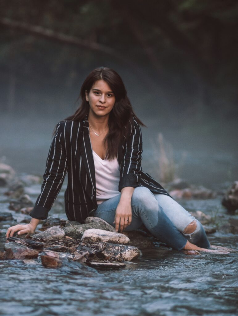 woman in black and white striped blazer sitting on rock